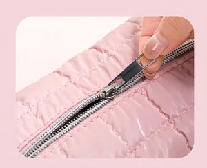 Macro-opname van een zilveren rits op een roze gewatteerde make-up tas voor op reis
