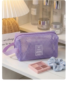 Détail d'une trousse de toilette en maille violette avec poignée et étiquette Travel