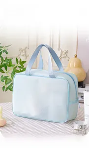 Close-up of light blue mesh toiletry bag with wide handle on a bathroom countertop