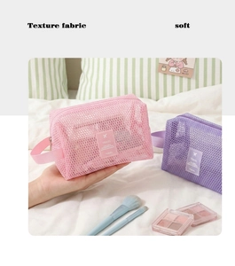 Détail des trousses de toilette en maille rose et violette sur un lit pour le voyage