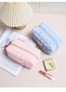 Gewatteerde glanzende make-uptassen in roze en blauw op een tapijt met accessoires