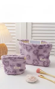Detail of two-piece purple plush heart makeup bags with floral zipper and soft texture