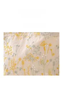 Détail de la broderie florale sur une trousse en lin beige avec étiquette tissée