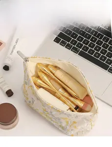 Détail de broderie florale sur trousse à maquillage en lin avec intérieur spacieux