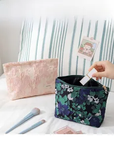 Détails de broderie sur trousse à maquillage en lin avec motifs floraux et étiquette