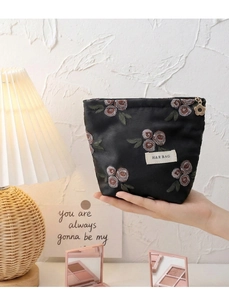 Détail de la pochette en lin noir avec broderie florale et fermeture éclair fleur dorée