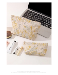 Détail de la broderie florale sur trousses de toilette en lin beige avec cosmétiques