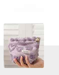Detail of purple plush makeup bag with heart patterns and gold floral zipper