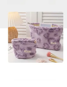 Detail of two plush purple heart patterned makeup bags with soft texture and metal zippers