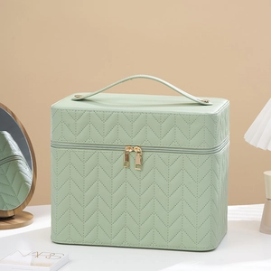 Detail of light green makeup bag with quilted herringbone pattern and dual zippers