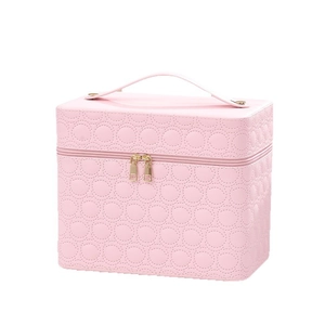Pink quilted PU makeup case with circular patterns and gold zippers on white background