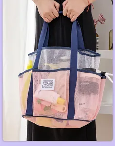 Close-up of pink and white mesh beach bag with items showing spacious interior storage