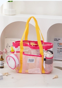 Detail der rosa Strandtasche aus Netzstoff mit gelben Gurten und kleiner runder Tasche