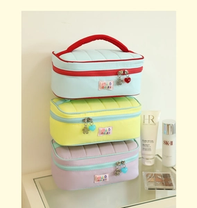 Close-up of quilted cosmetic bags with brand embroidery and colorful flower zipper pulls