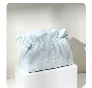 Dettaglio della borsa da trucco jacquard azzurro con fiocco laterale su base bianca