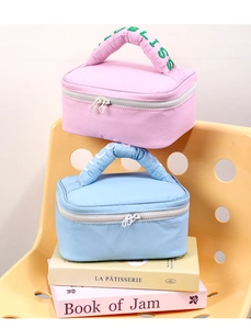 Close-up of quilted macaron cosmetic bags with Bliss embroidered handles and dual zippers