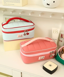 Detail of quilted cosmetic bags with heart charms and fabric handle in soft pastel colors