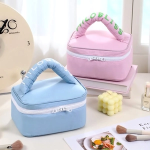 Pastel quilted cosmetic bags in pink and blue with fluffy handles for travel storage