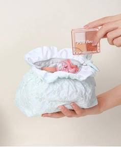 Dettaglio trousse in pizzo verde menta con fiocco e chiusura a zip per cosmetici