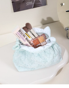 Dettaglio della trousse in pizzo blu con chiusura a coulisse e ricami floreali delicati