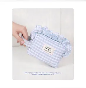 Detail of blue and white plaid cosmetic bag with pleated lace edges and hand strap