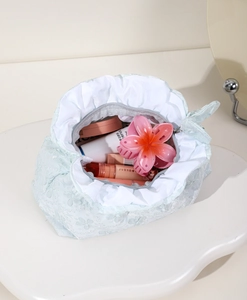 Dettaglio della borsa da toilette in pizzo celeste con trama floreale e fiocco decorativo