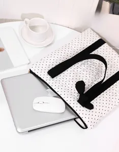 Quilted polka dot laptop sleeve with bow detail and black handles in a workspace setup