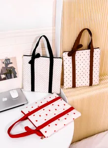 Close-up of quilted tote bags with heart and polka dot patterns and decorative bows