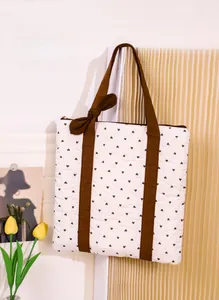 Detail showing reinforced brown fabric handles and quilted heart pattern on white tote bag