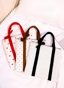 Detailed view of three quilted tote bags with heart and polka dot prints and bow straps