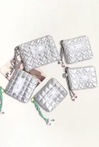Dettaglio di trousse trapuntate argento con motivi a cuore e laccetti intrecciati
