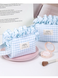 Detail of blue and white checkered makeup bag with ruffled edges and convenient handle strap