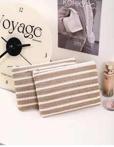 Close-up of woven striped makeup bags with metal zipper and natural straw texture