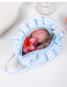 Detail showing spacious blue plaid makeup bag with ruffles and cosmetics inside
