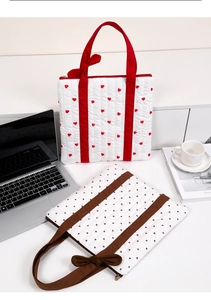 Quilted heart tote bags with red and brown straps on a desk with laptop and coffee