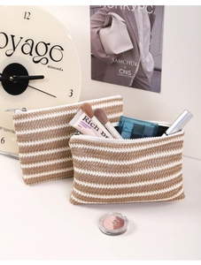 Detail of two striped woven makeup bags with metal zippers and travel essentials