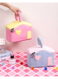 Detail of house-shaped makeup bags with heart embroidery and golden bell zippers