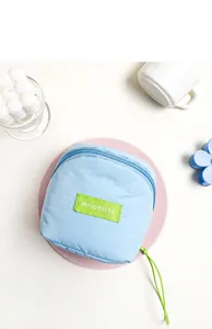 Macro shot of light blue cloud makeup bag showing green label and zipper detail