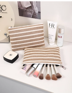 Close-up of beige and brown striped woven makeup bag with a silver metal zipper closure