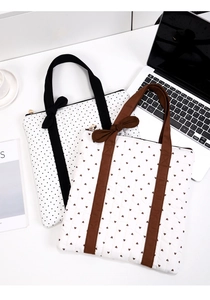 Polka dot and heart quilted laptop bags with bow straps on a desk with office accessories