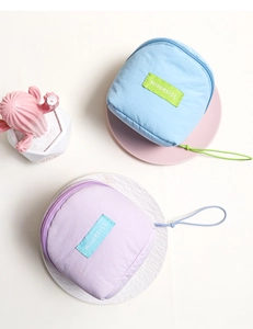 Detail of macaron-colored cloud cosmetic bags in blue and purple with woven logo labels