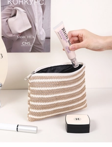 Detail of the striped woven makeup bag texture with metal zipper and travel essentials