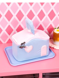 Close-up of heart-shaped metal zippers on house-shaped quilted cosmetic bag
