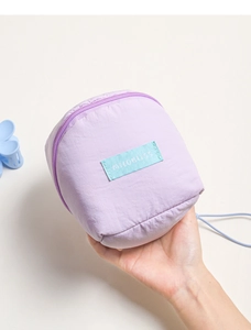 Close-up of a purple quilted nylon cosmetic pouch with a blue woven brand label