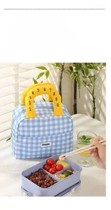 Close-up of blue plaid insulated lunch bag featuring yellow handles and Dream label