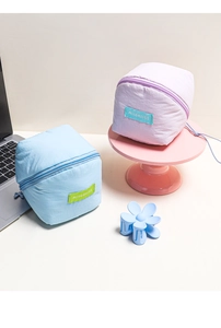 Detail of quilted cloud makeup bags in pastel blue and lilac with zipper and brand label