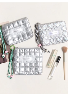 Dettaglio di pochette cosmetiche argento trapuntate con cordini intrecciati e perline