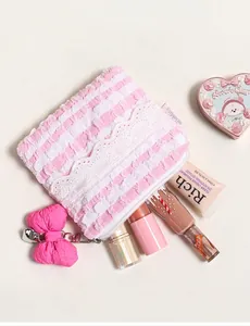 Detailansicht der rosa gestreiften Kosmetiktasche mit weißer Spitze und Schleifenanhänger