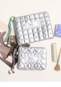 Dettaglio di pochette cosmetiche trapuntate argento con cuori iridescenti e laccetti intrecciati