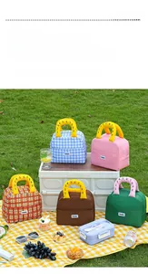 Close-up of colorful checkered lunch bags with unique handle design in outdoor picnic setting